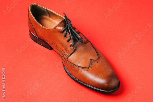 Mens shoes. Brown leather shoes isolated on a red background. Boots made of genuine leather close-up. Mens fashion