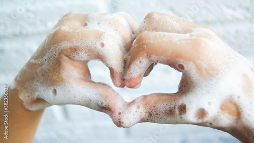 Washing hands with soap and foam. Heart-shaped fingers. Coronavirus pandemic protection by washing hands.