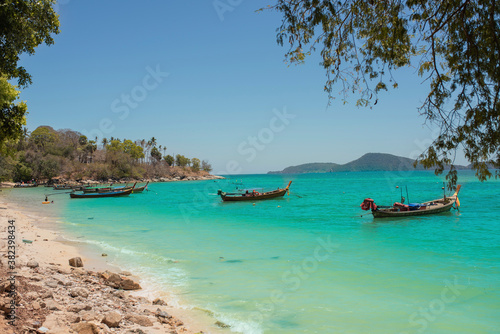 Fishing boats on the coast of the sea in Thailand on the island of Phuket. Andaman sea calm azure clean transparent magical white sand. On the shore are huge white yellow rock stones.green palm trees