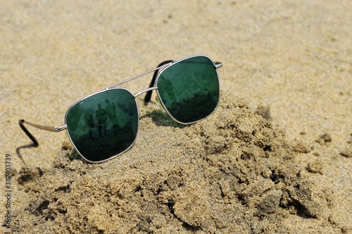 Reflecting sunglasses on a sandy beach in the summer, and the blue sky with people is reflected in glasses,