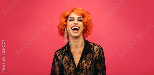 LGBTQ drag queen laughing on pink background