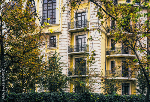 Autumn in the city. The facade of an old house and trees with yellowed leaves
