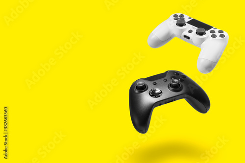 White and black game controllers on yellow background