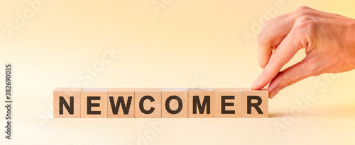 Woman made word NEWCOMER with wood blocks