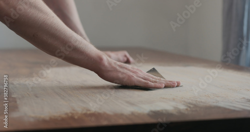 man hand sanding black walnut wood table