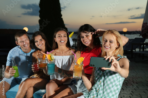 Happy people taking selfie at pool party in evening