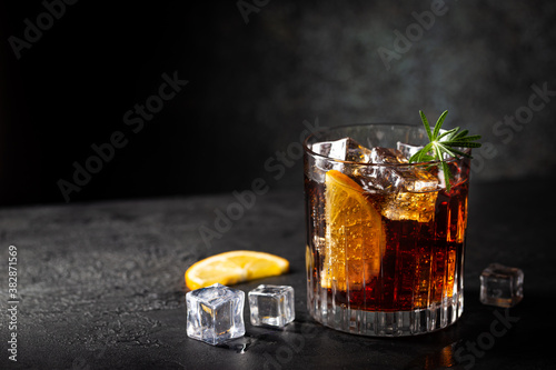 Fresh made Cuba Libre cocktail with brown rum, cola and lemon on wooden background