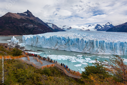 Tourists at viewpoint.Perito Moreno glacier frozen ice field. Autumn Yellow trees. Lake Argentina. 