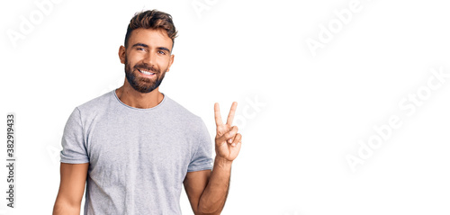 Young hispanic man wearing casual clothes smiling looking to the camera showing fingers doing victory sign. number two.