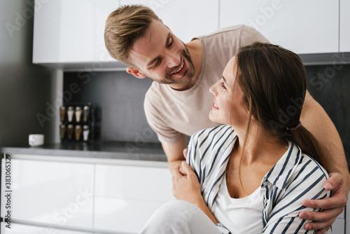 Young beautiful caucasian couple smiling and hugging together at home