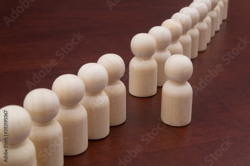 Wooden figures of people stand in a row. One figure standing out from the crowd. Leadership, talent, successful choice concept.