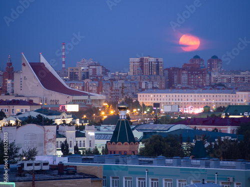 Full pink moon rising over the musical theater. Omsk city center, Lenin square.