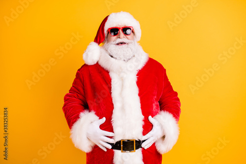 Portrait of his he nice funny glad cheerful cheery white-haired Santa big belly stomach abdomen laughing ho-ho having fun isolated bright vivid shine vibrant yellow color background