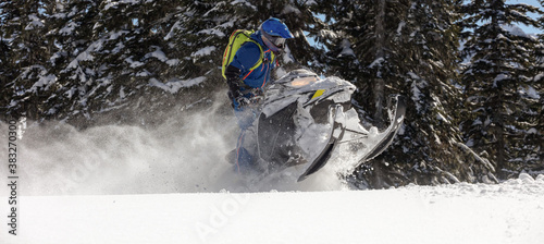 riding a mountain snowmobile in a high - altitude forest. Extreme snowmobilers Ride & Racing. a bright suit and a snow motorcycle. snow bike sports riding. Winter fun moto extreme. high res photo