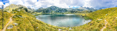Panoramic view of a beautiful natural lake on a hiking trail in the mountains. Llac del Circ de Colomers, Pirineus, Salardú, Naut Aran, Val d'Aran, Lleida, Catalonia, Spain.