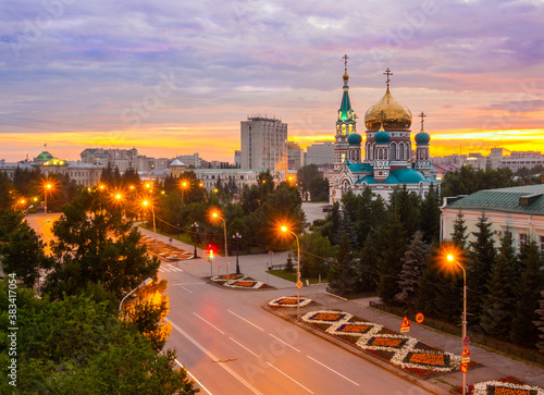 Assumption Cathedral in Omsk at beautiful orange-pink sunset. Holy Assumption Cathedral and Lenin Street