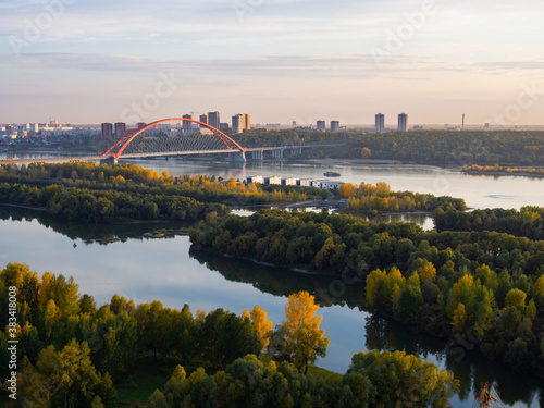 Bugrinsky bridge over the Ob River in Novosibirsk at sunset. A bridge with an orange arch over a river.