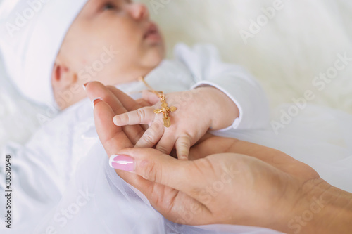 The sacrament of the baptism of a child. The kid is holding a cross. Selective focus.