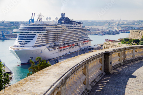 Mega modern MSC cruiseship or cruise ship liner in port of Valletta, Malta island with panoramic scenic view of historic old town, city walls and fortress skyline on summer day during Med cruising