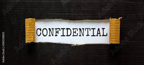 The word 'confidential' appearing behind torn black paper. Business concept.