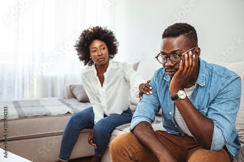 Cropped shot of an unhappy young couple after a fight at home. Unhappy young millennial married couple sitting on couch in living room after quarrel fight. 
