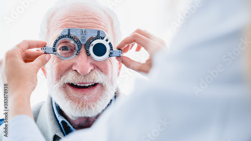Smiling elderly man checking up vision with special ophthalmic glasses