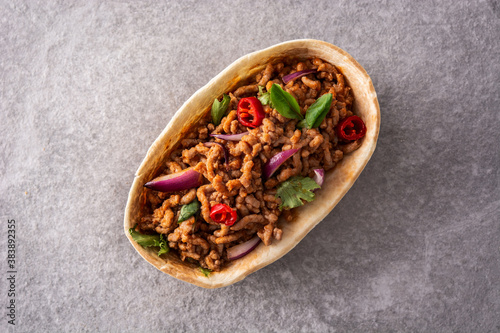 Mexican barquita taco with beef, chilli, tomato, onion and spices on gray stone 