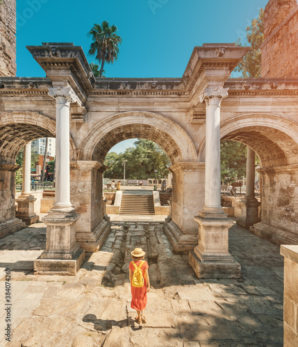 Happy female tourist traveler discover interesting places and popular attractions and walks in the old city of Antalya, Turkey. The famous Roman gate of Hadrian