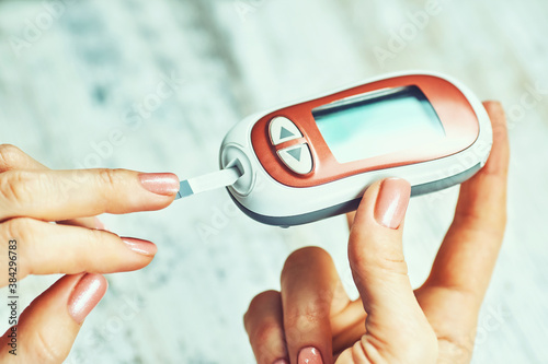 diabetic woman using blood glucose meter, female hands hold lancet pen glucometer on finger measure sugar check insulin