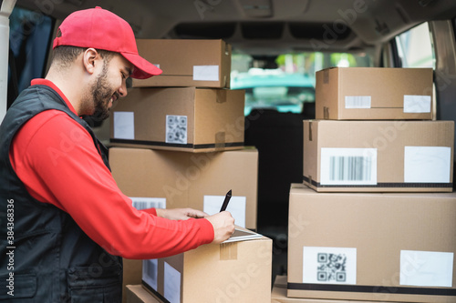 Happy courier man with signing on tablet for delivery boxes - Technology, tracking and shipment service concept - Focus on face