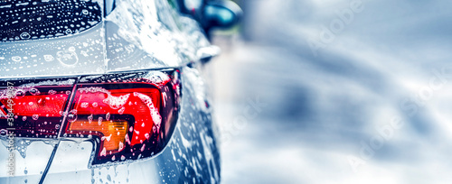 Manual car wash with white soap, foam on the body. Washing Car Using High Pressure Water.