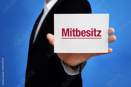 Mitbesitz. Anwalt (Mann) mit Karte in der Hand. Text/Wort auf Schild. Hintergrund blau.