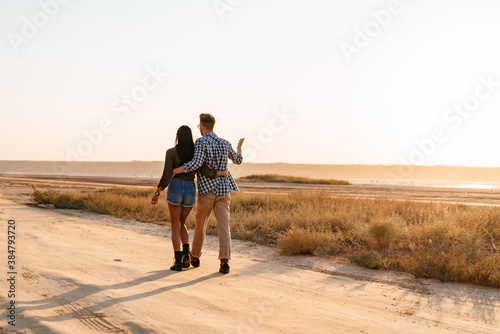 Beautiful young couple hugging while strolling on nature at summer