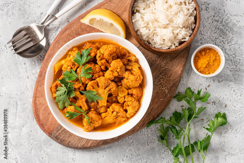 Cauliflower stew with curry, cumin, turmeric and other spices in a white bowl on a grey concrete background top view. Curry roasted cauliflower.