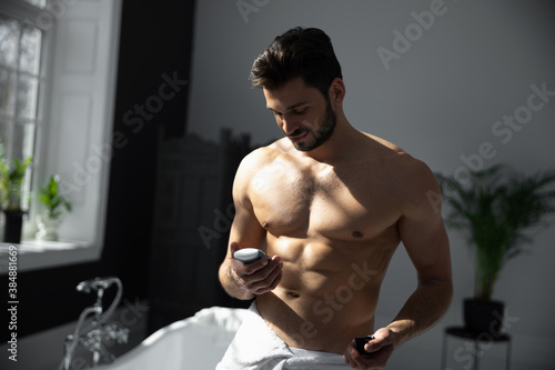 Young handsome man applying deodorant