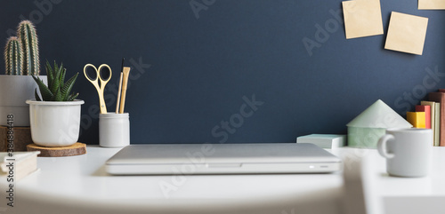 Table with laptop closed and blue wall background.