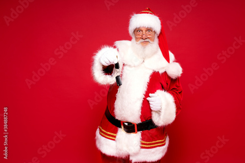 Happy Santa Claus with car keys as a gift.