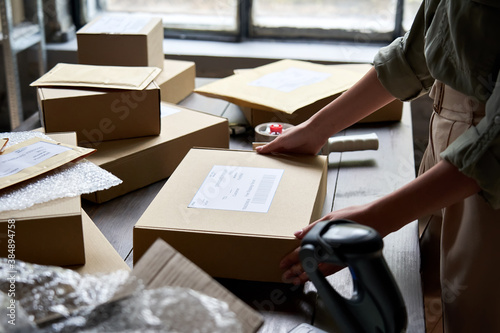 Female distribution warehouse worker or seller packing ecommerce shipping order box for dispatching, preparing post courier delivery package, dropshipping commerce retail shipment service concept.