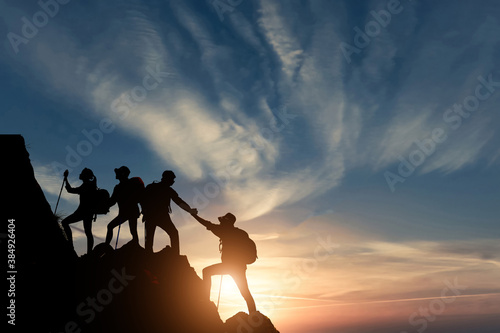 Silhouette male hiker groups celebrating success on top of a mountain in a majestic sunset and Two climber helping to hike up . Concept for success ,help, teamwork and Leadership concept .