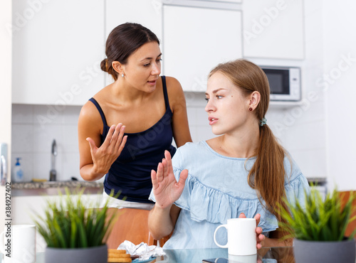 Emotional quarrel between two young women friends in kitchen interior