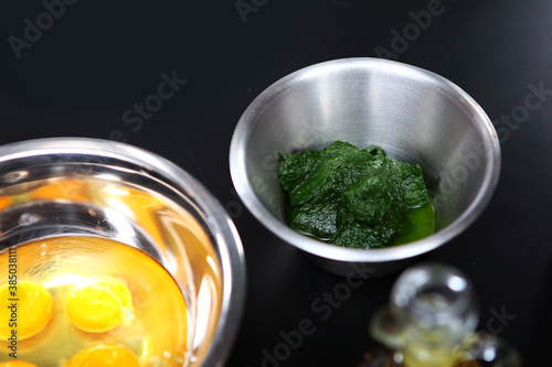 Ingredients for making homemade pasta with spinach. Spinach and eggs in a metal dish.Top view.