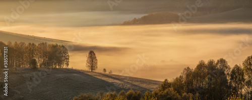 Autumn morning, panoramic view. Dawn light illuminates the misty valley.