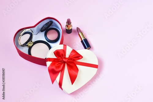 Gift box in the form of a heart with decorative cosmetics on a pink background. Concept beauty, holiday. Copy space. Flat lay.