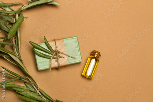 Jabón verde de aceite de oliva junto a una botella con aceite de oliva sobre un fondo marrón liso y aislado. Vista superior. Copy space