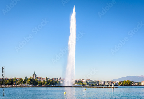 The cathedral is overlooking the city and bay of Geneva, Switzerland, with the Jet d'Eau, the emblematic 140 meter-high water jet fountain on the Lake Geneva, by a sunny summer morning.