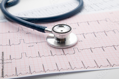 Blue Stethoscope on electrocardiogram (ECG) chart paper. ECG heart chart scan isolate on white. Healthcare insurance and medical background