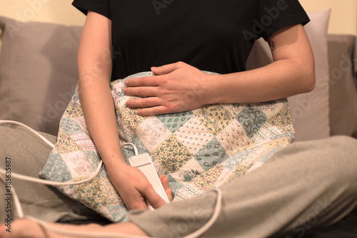 Una mujer utilizando una manta eléctrica para el dolor de estómago