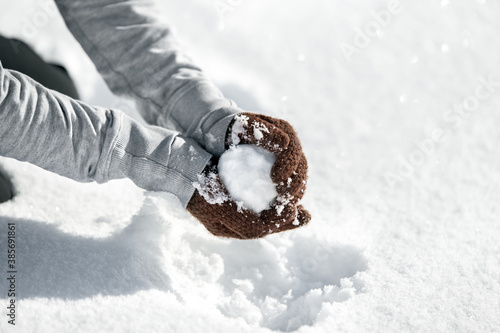 Woman forming a snowball for a funny fight, Winter game in the snow