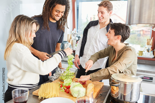 Laughing students prepare salad together in shared kitchen