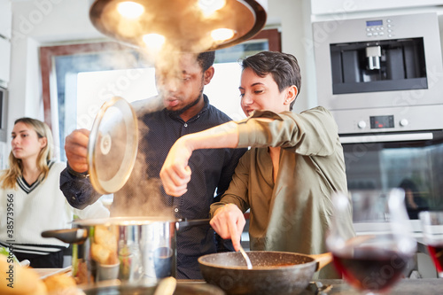 Friends cook pasta with sauce together in shared kitchen